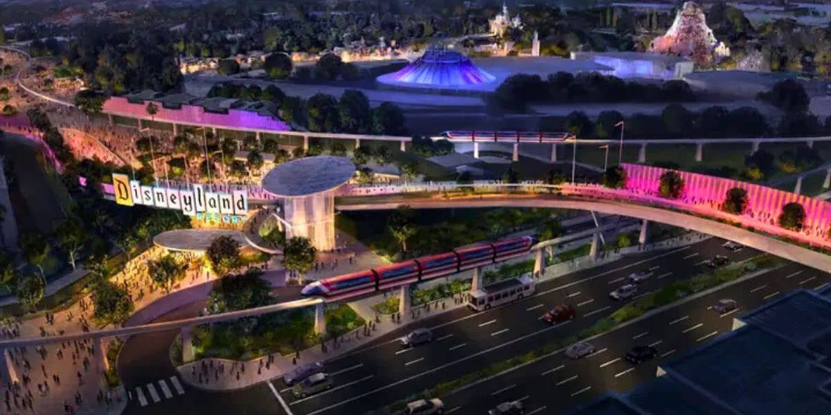 A vibrant aerial view of Disneyland at night, featuring a colorful entrance sign, illuminated pathways, monorail, crowded walkways, and iconic park attractions in the background.
